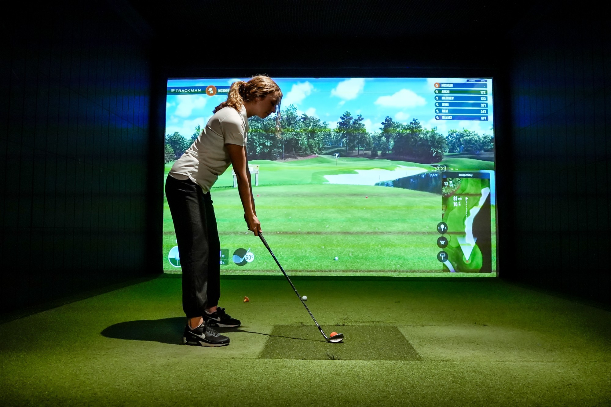 A league player teeing off with the live scoreboard on screen